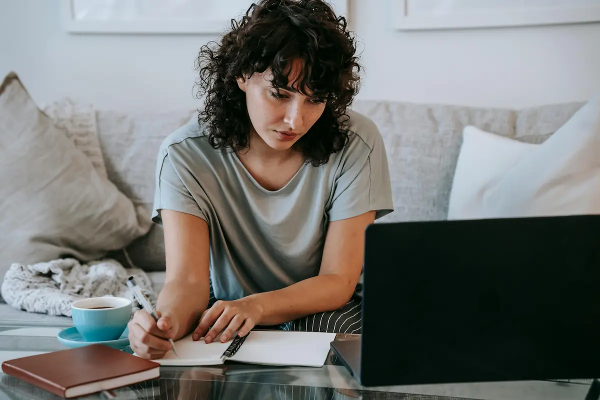 Student taking notes while researching whether online class help companies are legit